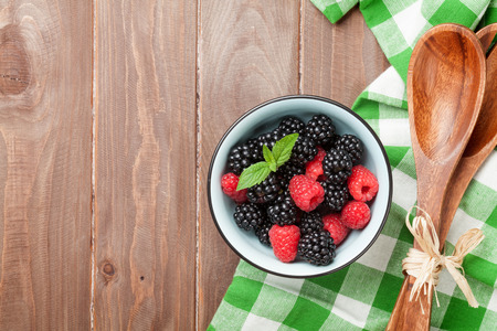 Blackberries and raspberries bowl on wooden table. Top view with copy spaceの写真素材