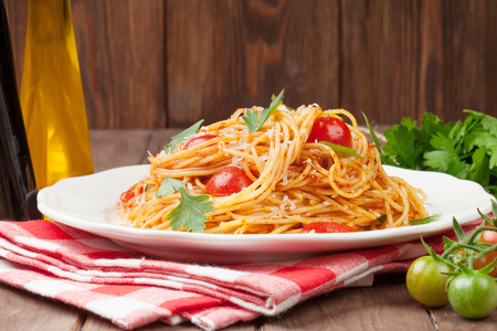 Spaghetti pasta with tomatoes and parsley on wooden tableの写真素材