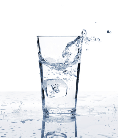 Glass of water with ice and splash. Isolated on white backgroundの写真素材