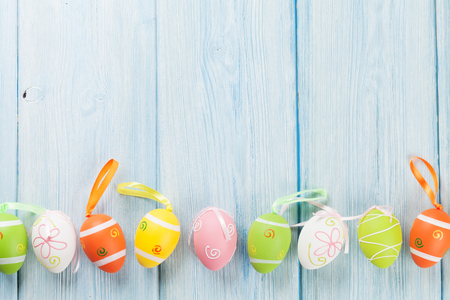 Easter background with colorful eggs over blue wooden table. Top view with copy spaceの写真素材