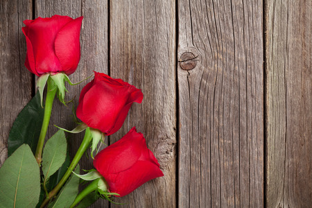 Red roses over wooden table. Valentines day background. Top view with copy spaceの写真素材
