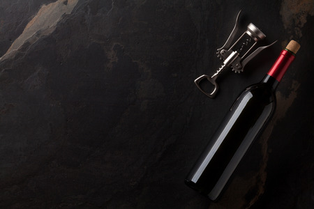 Red wine bottle and corkscrew on stone table. Top view with copy spaceの写真素材