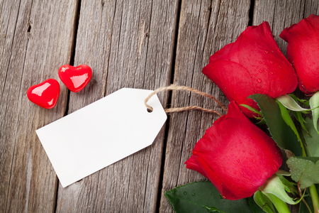 Red roses with tag and candy hearts over wooden table. Valentines day conceptの写真素材