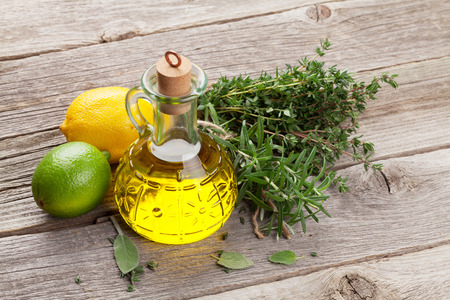 Olive oil and fresh garden herbs on wooden tableの写真素材
