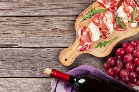 Prosciutto and mozzarella with red wine on wooden table. Top view with copy spaceの写真素材