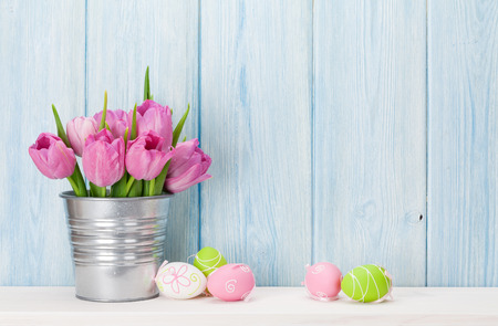 Easter eggs and tulips bouquet on shelf in front of wooden wall. View with copy spaceの写真素材