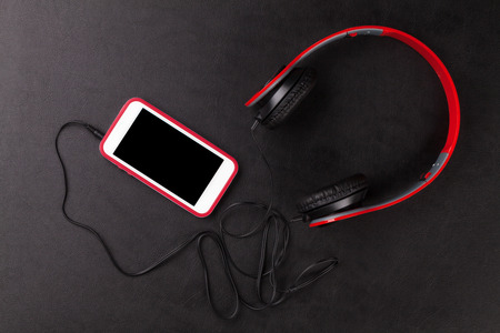 Smartphone and headphones on black leather deskの写真素材