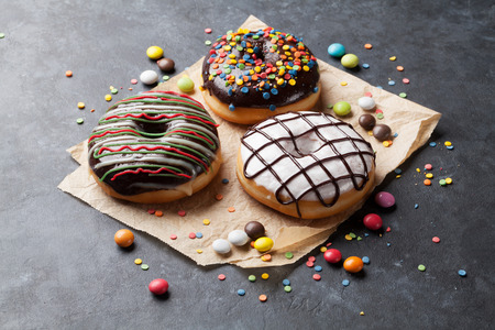 Colorful donuts and candies on stone tableの写真素材