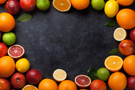 Fresh ripe citruses frame. Lemons, limes and oranges on dark stone background. Top view with copy spaceの写真素材