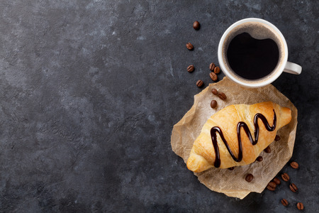 Fresh homemade croissant with chocolate and coffee on stone table. Top view with copy spaceの写真素材