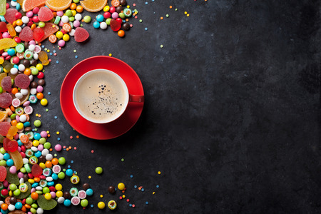Colorful candies, jelly and marmalade and coffee cup on stone background. Top view with copy spaceの写真素材