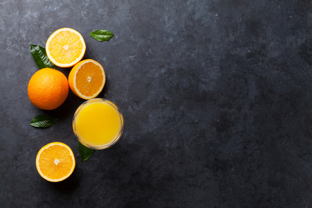 Fresh orange fruits and juice on stone table. Top view with copy spaceの写真素材