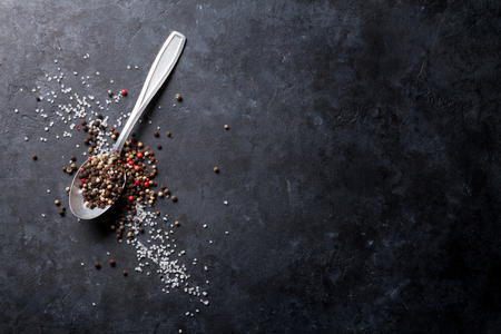 Black, white and red pepper and salt spice in spoon. Top view with copy spaceの写真素材