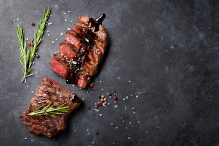 Grilled striploin sliced steak with salt and pepper over stone table. Top view with copy spaceの写真素材