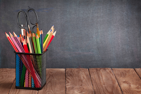 School and office supplies on classroom table in front of blackboard. View with copy spaceの写真素材