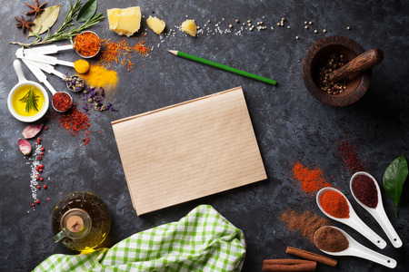 Herbs and spices over black stone background. Top view with notepad for copy spaceの写真素材
