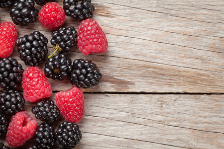 Blackberries and raspberries on wooden table background. Top view with copy spaceの写真素材
