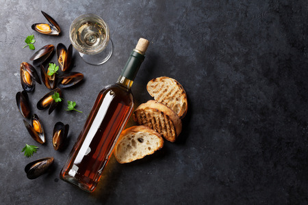 Mussels, bread toasts and white wine on stone table. Top view with copy spaceの写真素材