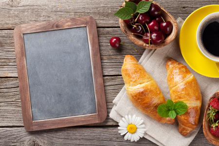 Blackboard, croissants, berries, flowers and coffee cup. Top view with copy spaceの写真素材