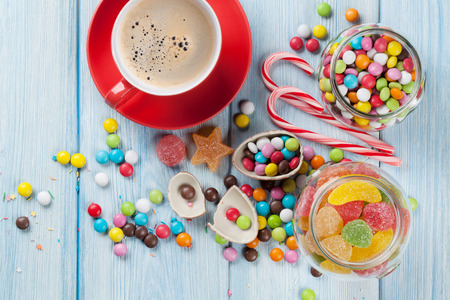 Colorful candies and coffee cup on wooden table background. Top viewの写真素材