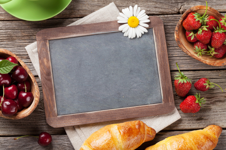 Blackboard, croissants, berries, flowers and coffee cup. Top view with copy spaceの写真素材