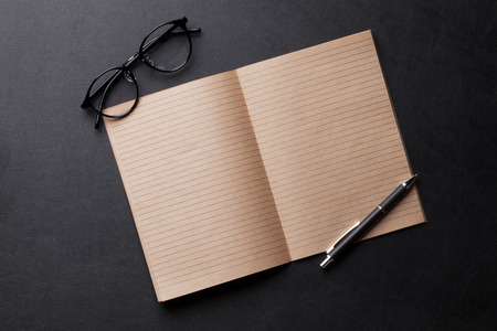 Office desk with notepad and glasses over leather texture. Top view with copy spaceの写真素材