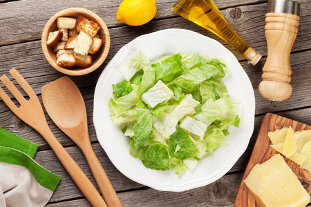 Fresh healthy caesar salad cooking on wooden table. Top viewの写真素材