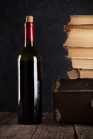 Red wine and old books on table in front of stone wallの写真素材