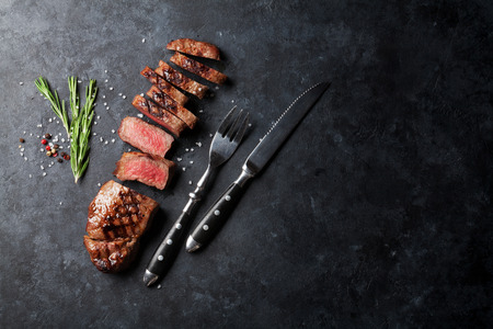 Grilled sliced beef steak on stone table. Top view with copy spaceの写真素材