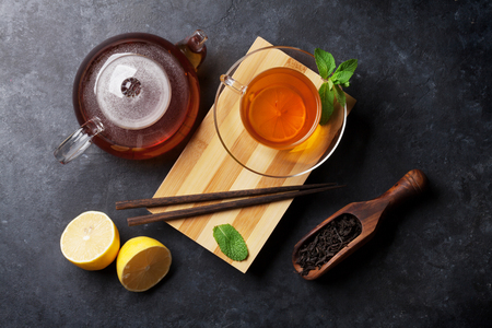 Tea cup, teapot and dry tea in spoon on stone table. Top viewの写真素材