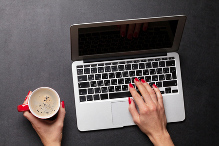 Female working on laptop with coffee cup. Top viewの写真素材