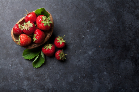 Fresh garden strawberry in bowl on stone table. Top view with copy spaceの写真素材