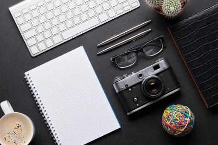 Office desk with photo camera, pc, notepad, glasses, pen and pencil. Top view with copy spaceの写真素材