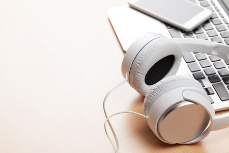 Headphones over laptop on wooden desk table. Music concept. View with copy spaceの写真素材