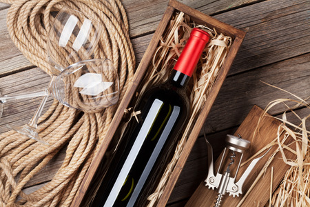 Red wine bottle in box and glasses on wooden table. Top viewの写真素材