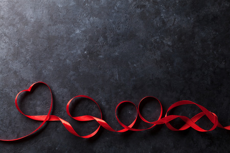 Valentines day greeting card. Heart shaped red ribbon on stone background. Top view with copy spaceの写真素材