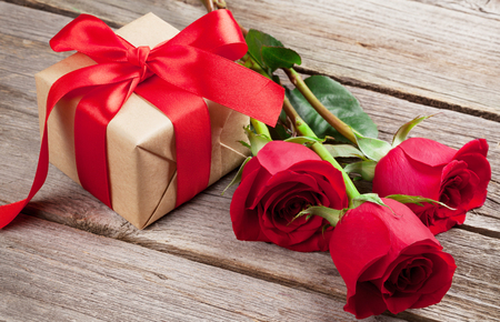 Valentines day greeting card. Red roses and gift box on wooden tableの写真素材