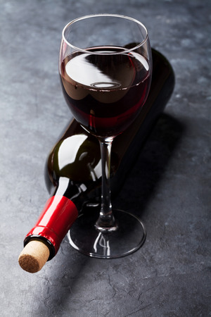 Red wine glass and bottle on stone backgroundの写真素材