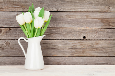 White tulips bouquet in front of wooden wall. With space for textの写真素材