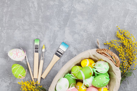 Colorful easter eggs and brushes on stone table. Top view with copy space