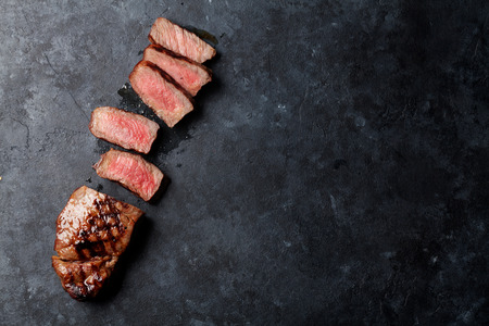 Grilled sliced beef steak on stone table. Top view with copy spaceの写真素材