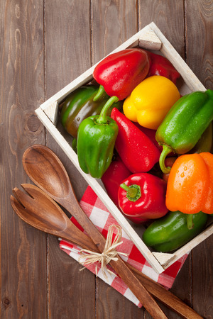 Fresh colorful bell pepper box on wooden table. Top viewの写真素材
