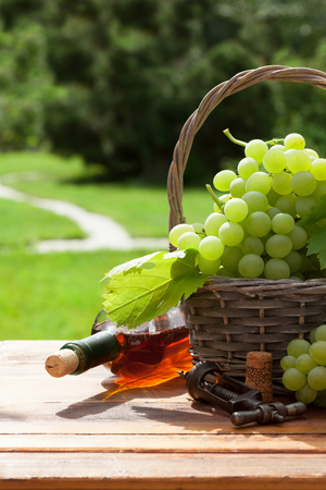 White grape and bottle of wine on wooden table in sunny gardenの写真素材