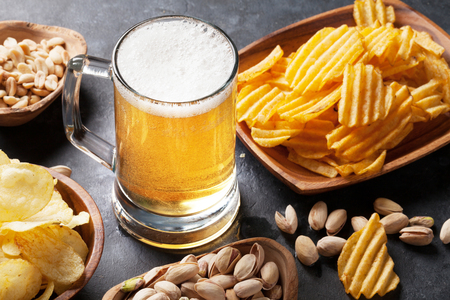 Lager beer and snacks on stone table. Nuts, chipsの写真素材