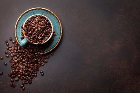 Coffee cup with beans on stone background. Top view with copy space for your text