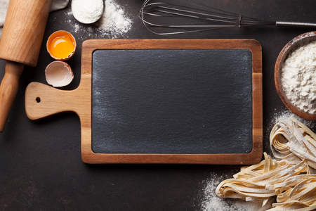 Pasta cooking ingredients on kitchen table. Top view with blackboard for your textの写真素材