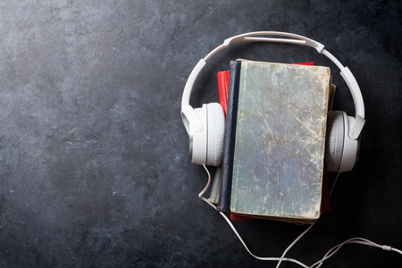 Audio book concept. Headphones and old books over stone table. Top view with space for your textの写真素材