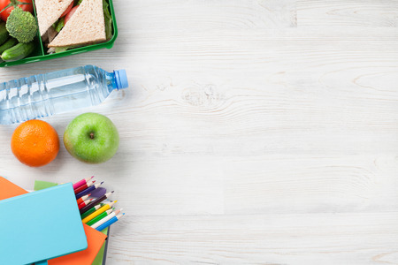 Lunch box with vegetables and sandwich on wooden table. Kids take away food box and school supplies. Top view with copy spaceの写真素材