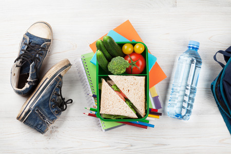 Lunch box with vegetables and sandwich on wooden table. Kids take away food box and school supplies. Top viewの写真素材