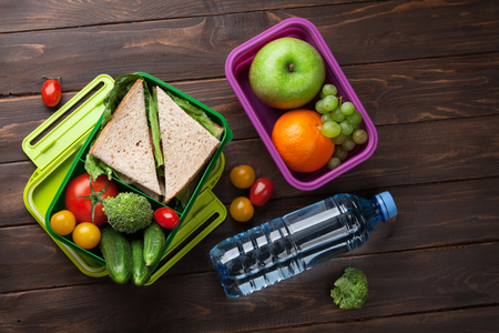 Lunch box with vegetables and sandwich on wooden table. Kids take away food box. Top viewの写真素材